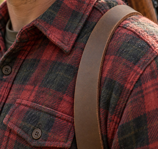 One-inch brown leather rifle sling worn over a red plaid flannel shoulder