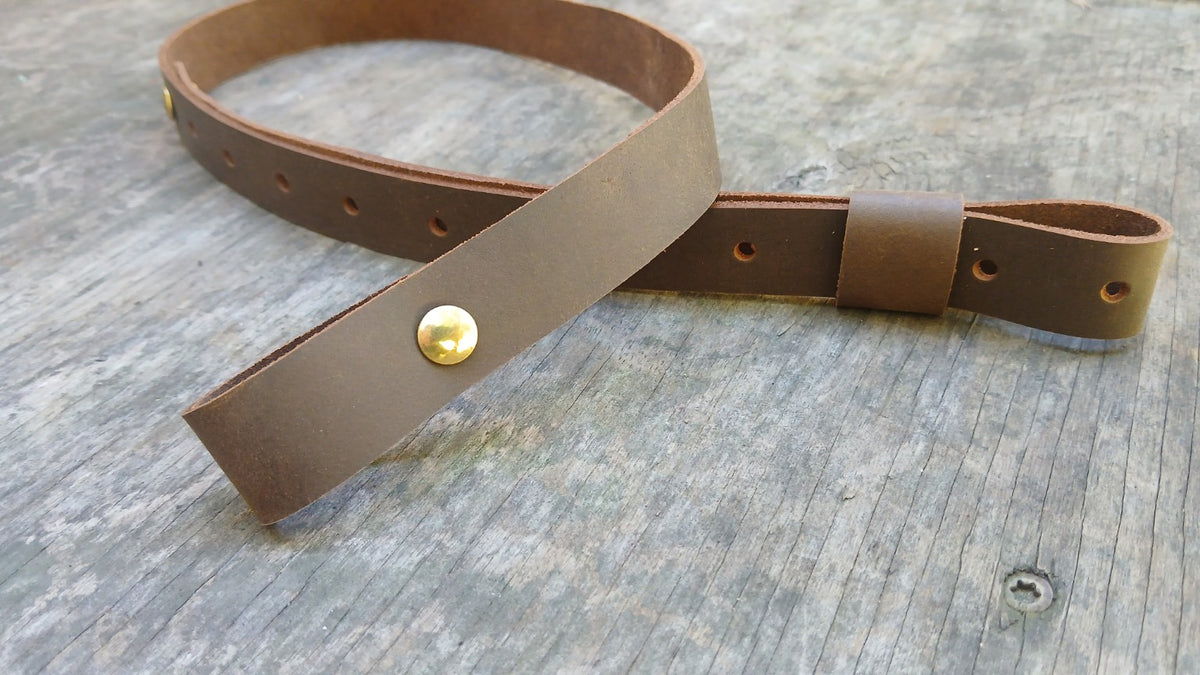 Close-up of brown leather rifle sling with adjustment holes brass rivets and keeper